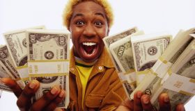Young man holding bundles of US dollars, smiling, portrait