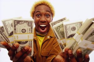 Young man holding bundles of US dollars, smiling, portrait