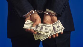 Handcuffed businessman holding cash