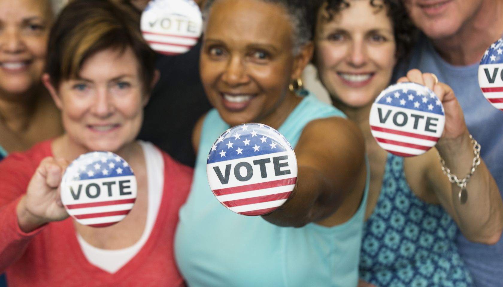 Senior friends holding Vote' buttons