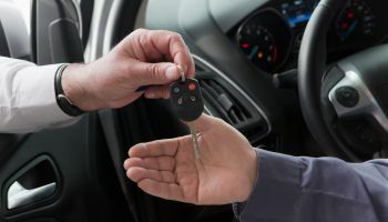 Hispanic car salesman handing keys to customer
