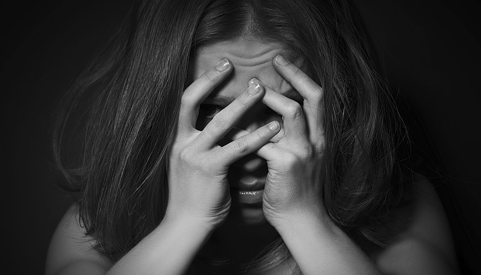 sad woman in depression and despair crying covered her face on black dark background