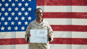 Black soldier holding I am strong sign near American flag