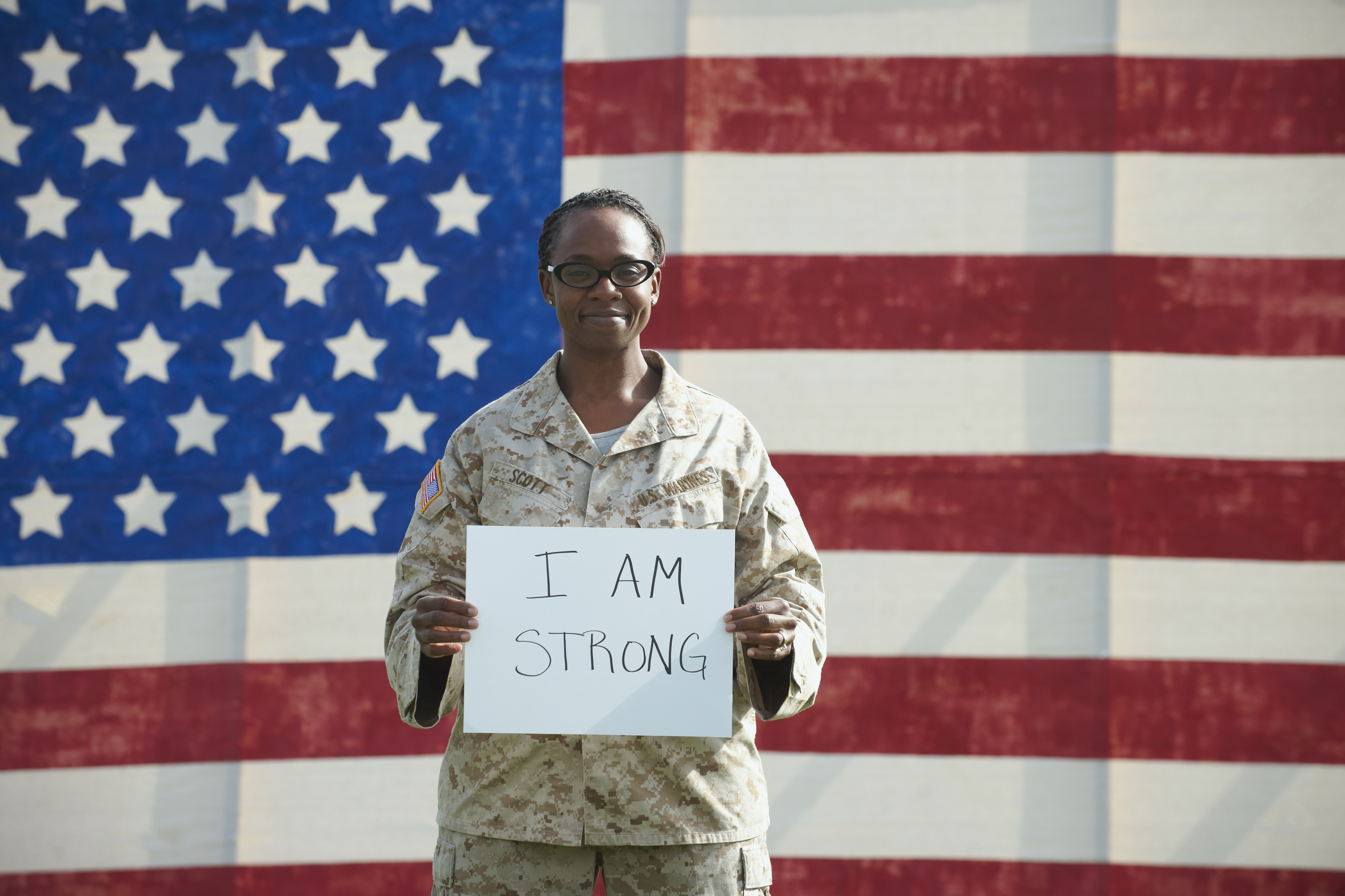 Black soldier holding I am strong sign near American flag