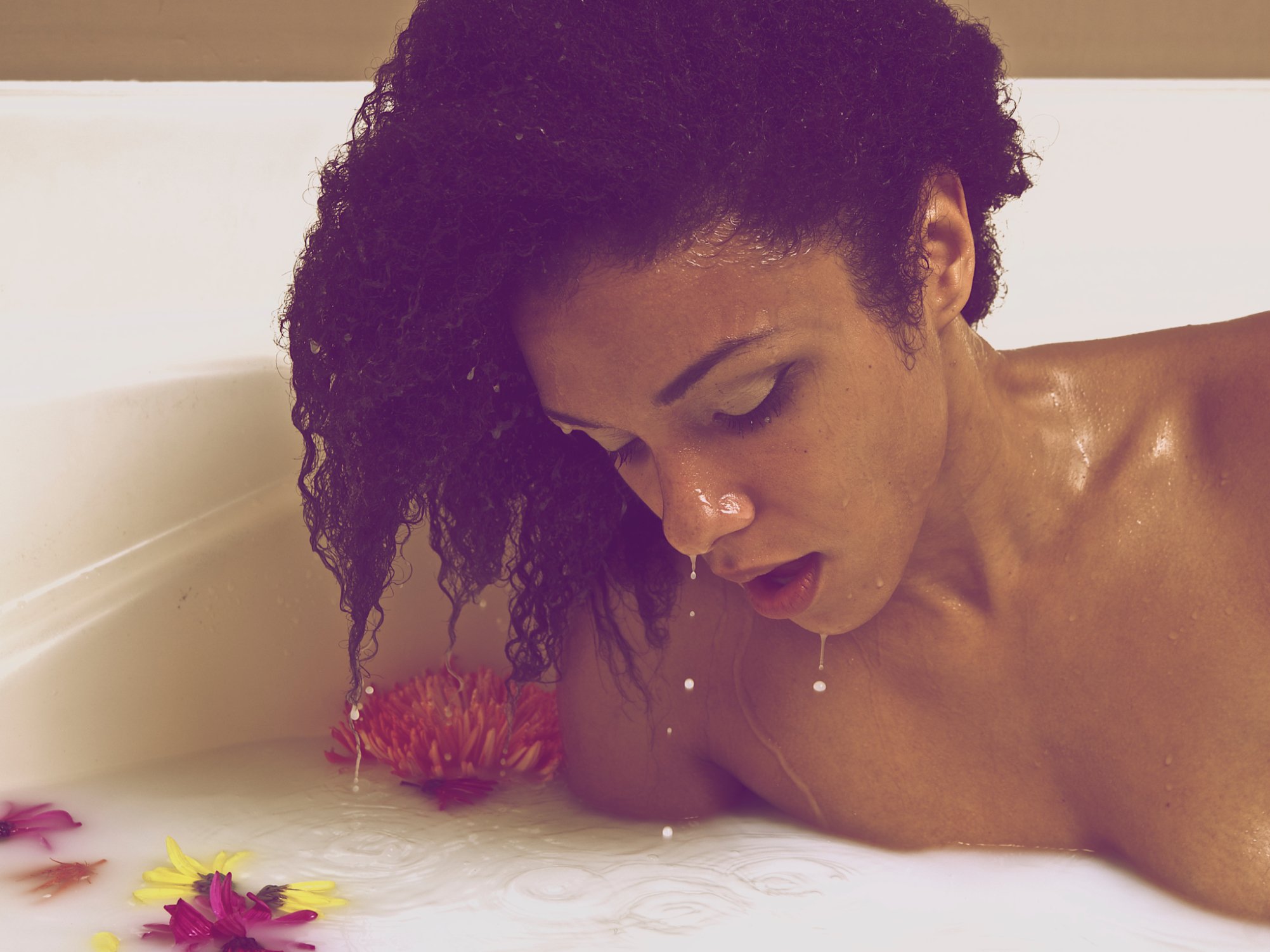 Close-Up Of Milk Dripping From Young Woman Face In Bathtub