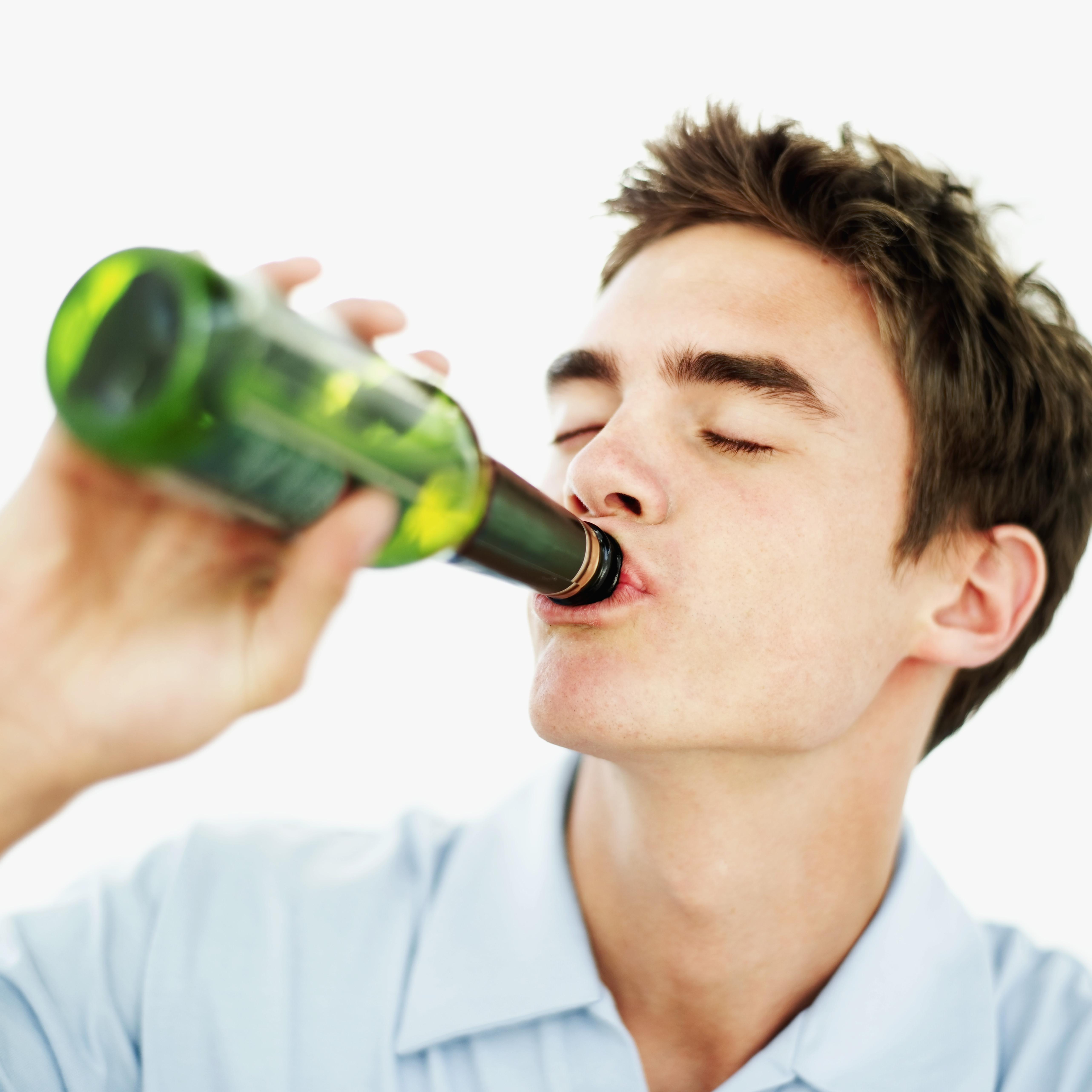 close-up of a teenage boy drinking a bottle of beer