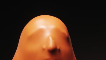 Impression of man's face through orange rubber, close-up