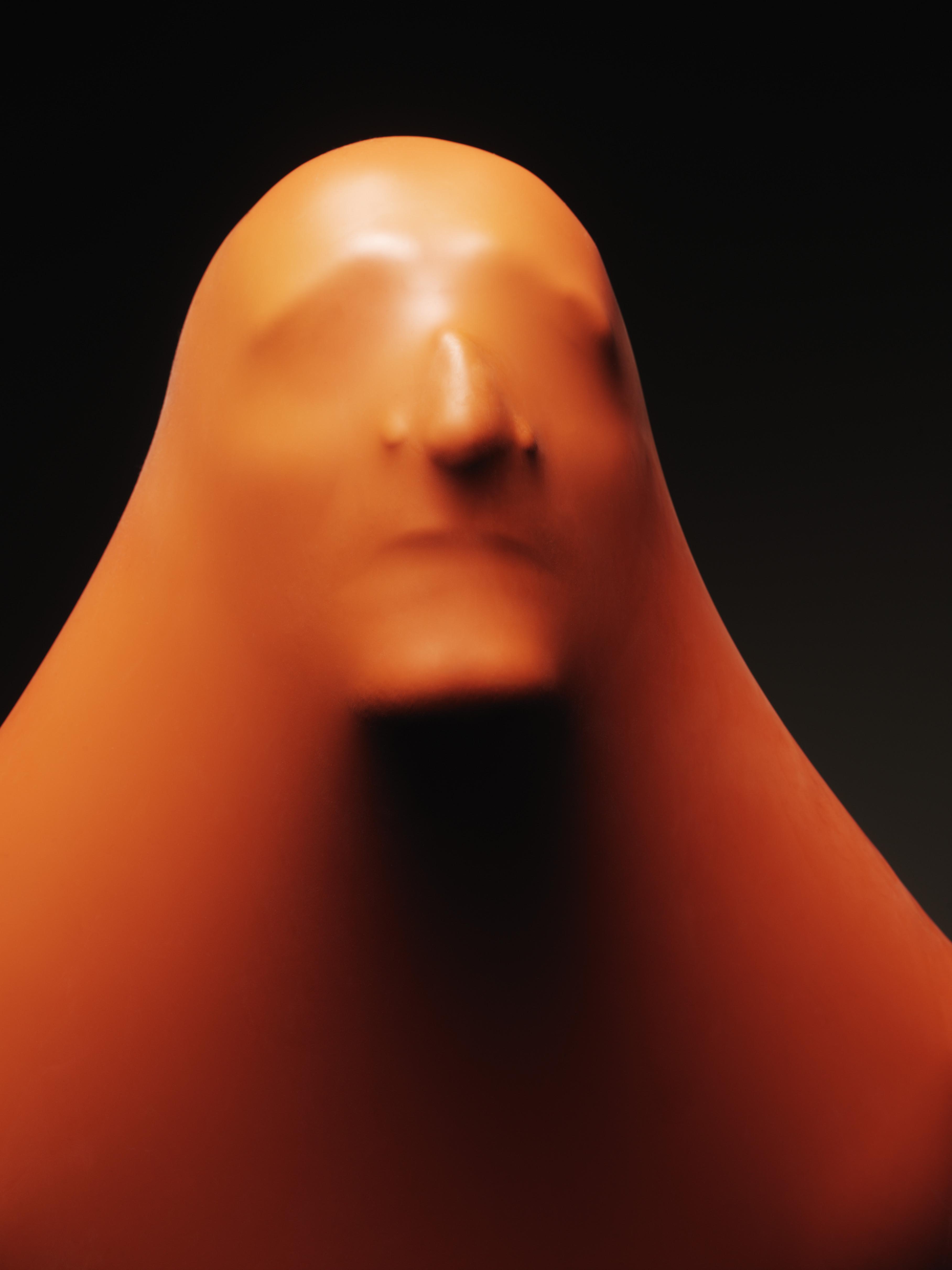Impression of man's face through orange rubber, close-up