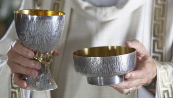 Priest holding goblet and communion bowl