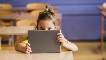 Cute schoolgirl using digital tablet on a class at elementary school.