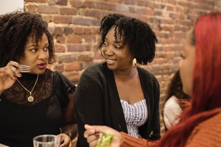 Women chatting and eating Thanksgiving dinner.