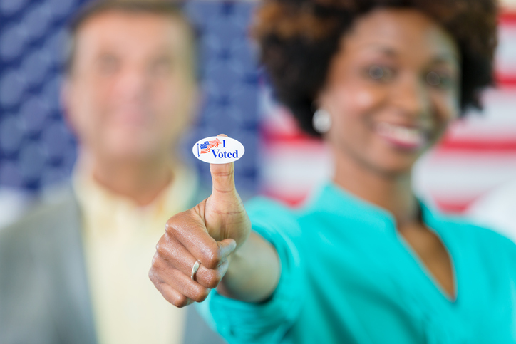 Voter gives a thumbs up with I voted sticker