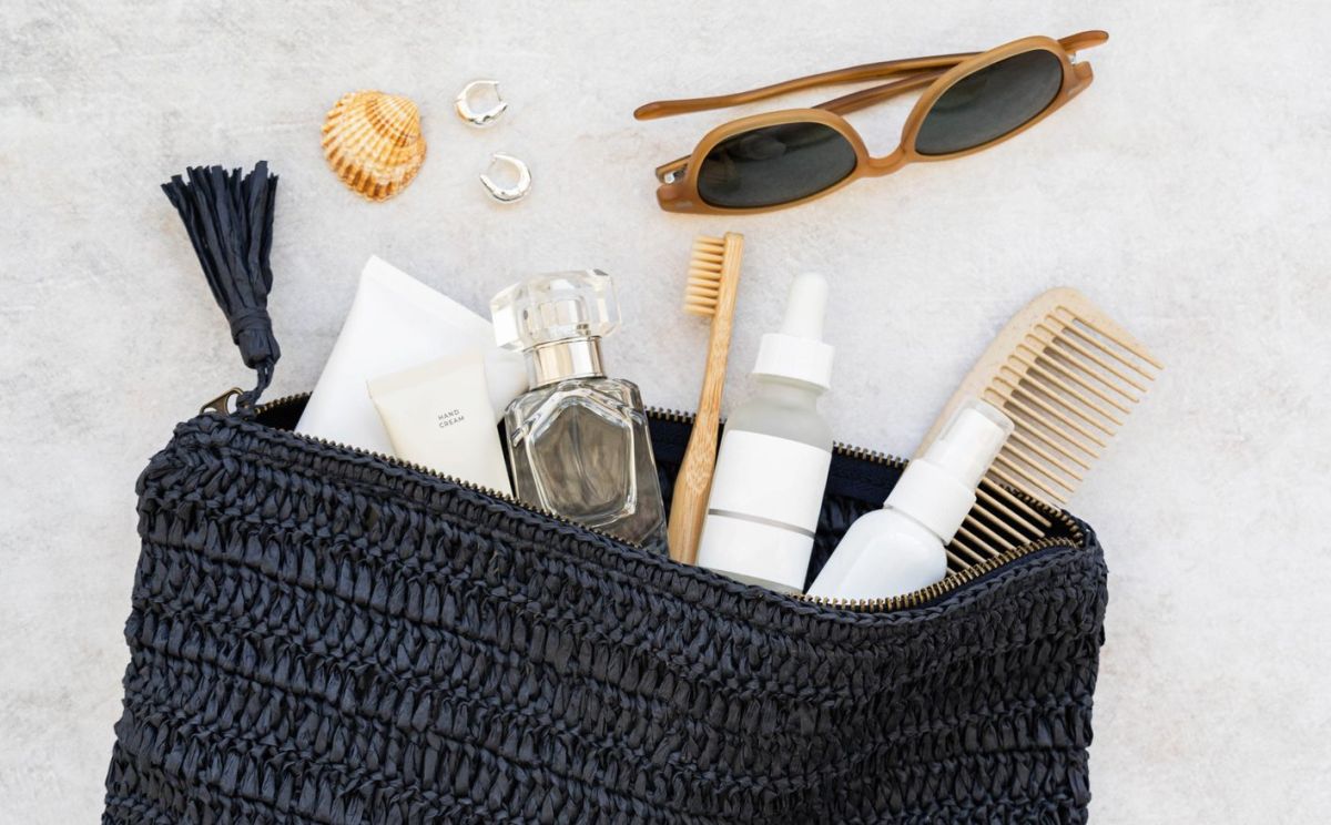 Open blue cosmetic bag filled with travel essentials, including sunglasses, bottles, comb, toothbrush
