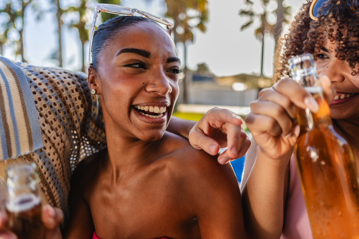 Young women friends enjoying drinks by the pool