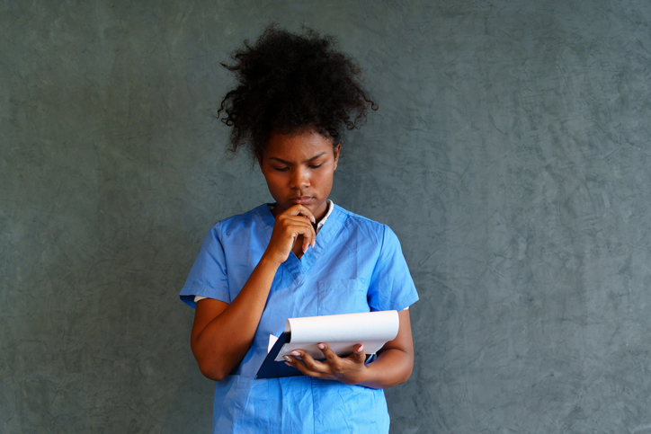 A tanned nurse is caring for a patient standing on a black background.
