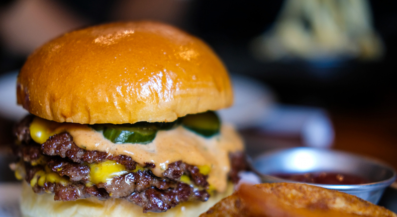 Double beef burger with mayo sauce and pickled cucumbers