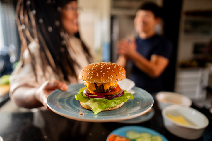 Close-up of woman holding a plate with hamburguer at home