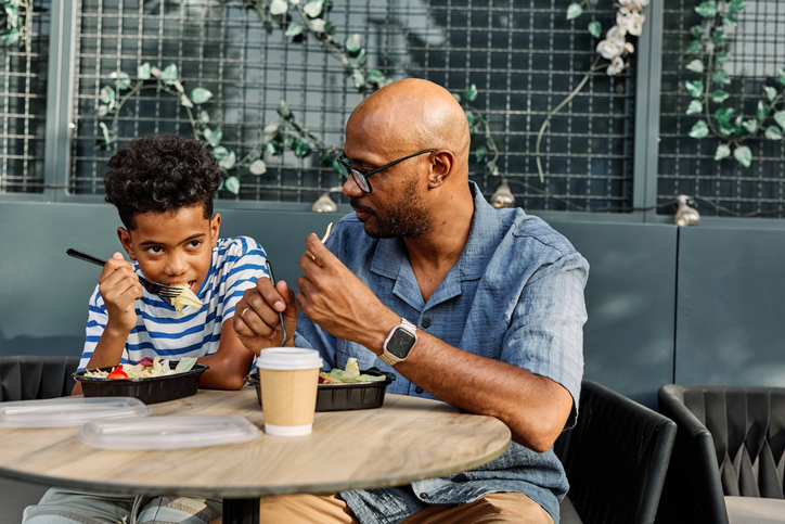 father child son family man boy together bonding parent outside african american teen dad table break meal salad food eating