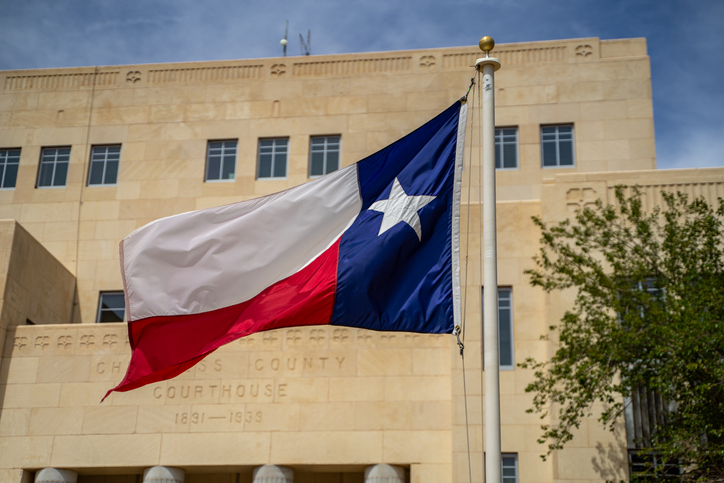 Large Texas Flag Blowing in the Wind in Front of Courthouse Building in Childress, Texas