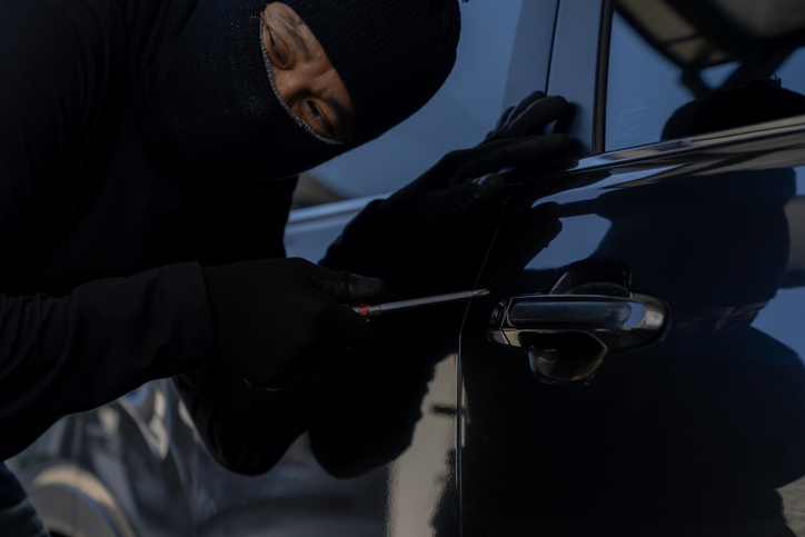 Thief in Black Outfit Breaking into Car at Night Parking Area