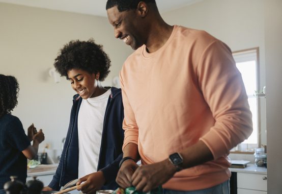 Smiling father and son preparing food in kitchen at home
