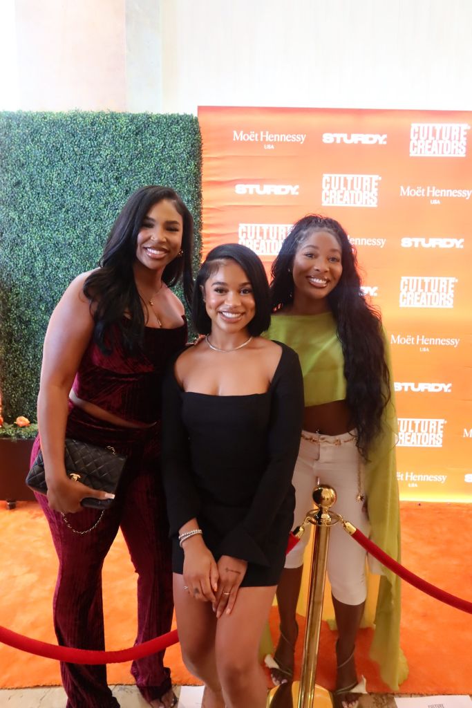 Three smiling women posing in front of a backdrop with "Culture Creators" and "Moët Hennessy" branding.