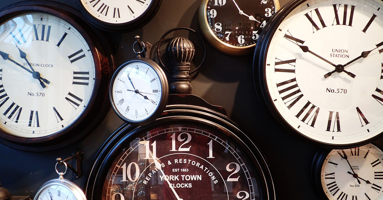 An assortment of vintage clocks and timepieces, including a "York Town Locks" clock, displayed on a dark background.