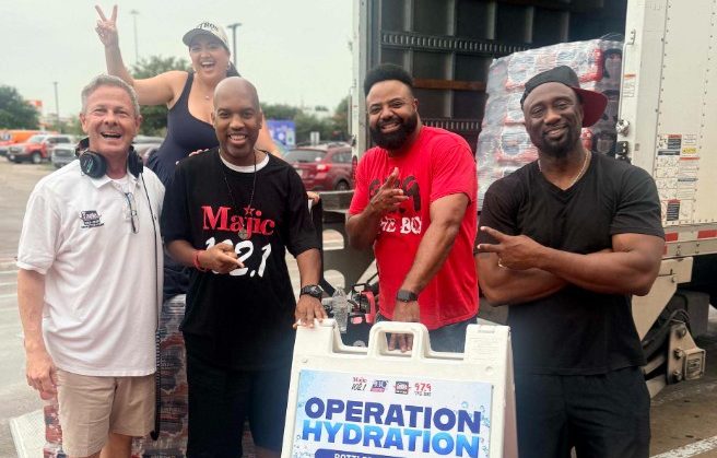 A group of smiling people standing in front of a truck with a sign for "Operation Hydration" water drive.