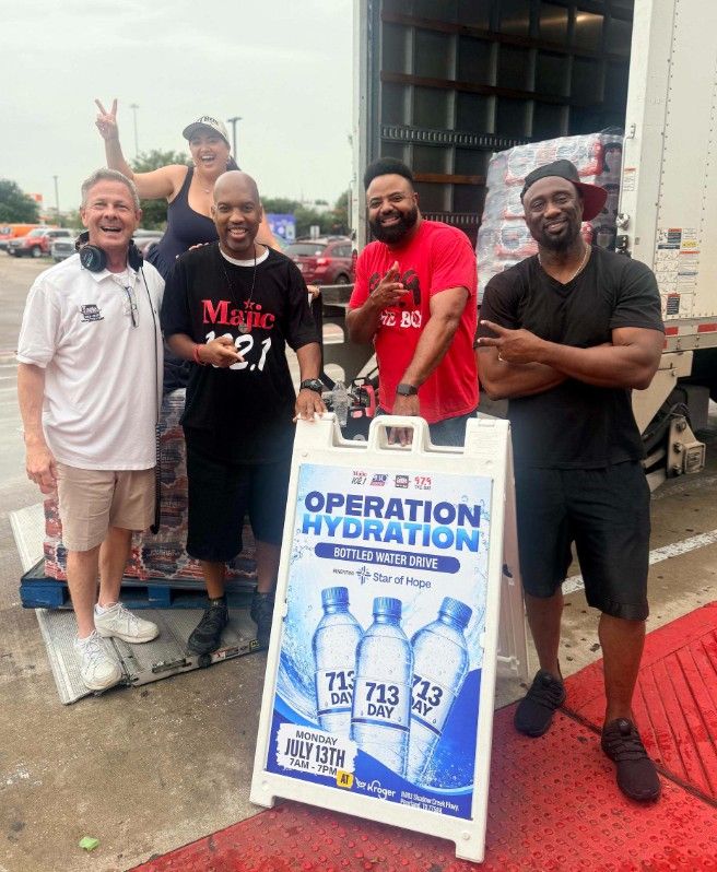 A group of smiling people standing in front of a truck with a sign for "Operation Hydration" water drive.