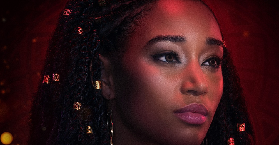 A close-up portrait of a young woman with dark skin, braided hair, and dramatic makeup against a red background.