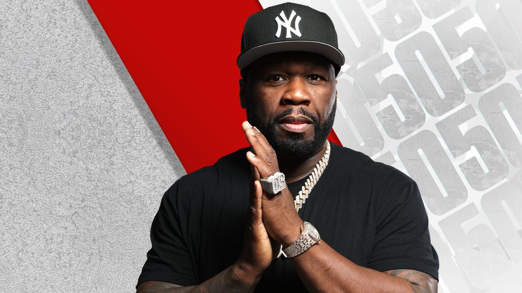 A Black man wearing a New York Yankees baseball cap and jewelry, posing with a serious expression against a red and gray background.